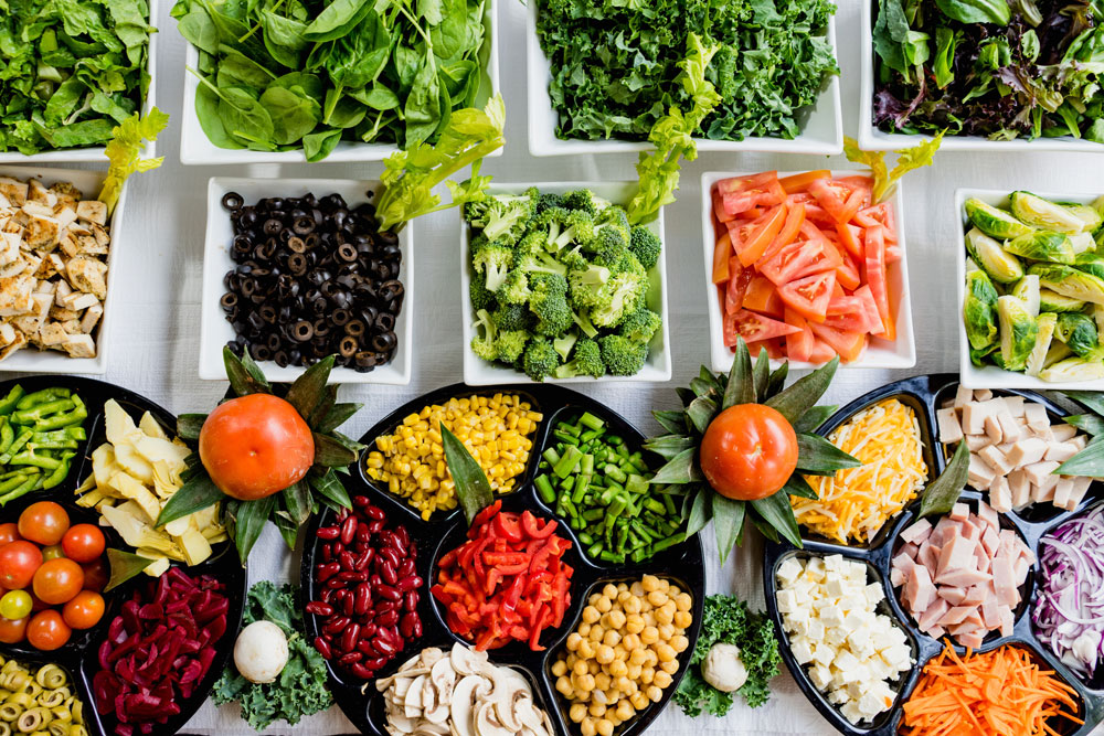 Salatbuffet mit frischem Gemüse, Salaten und Kräutern in Schalen
